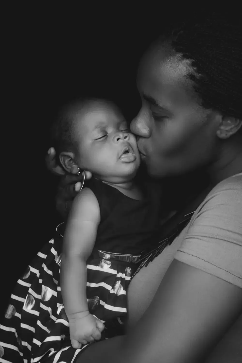 A mother kisses her sleeping baby on the cheek
